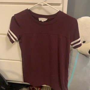 Maroon T-Shirt, white strips on sleeves.